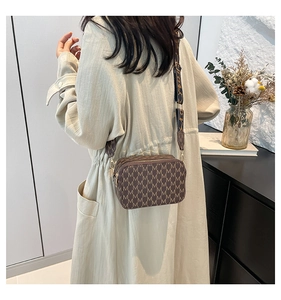 Detail of vintage monogram crossbody bag with M-pattern on beige trench coat outfit