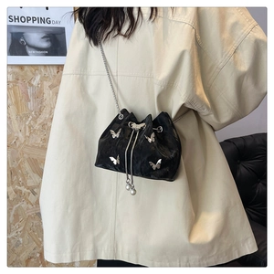 Detail of black velvet bucket bag with silver butterfly studs and pearl drawstring