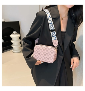 Detailed macro view of pink camera bag with letter pattern and wide jacquard shoulder strap