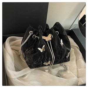 Close-up of black pleated bucket bag featuring silver butterfly buckles and pearl drawstring