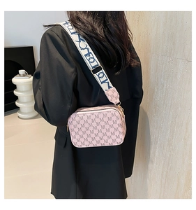 Detail of pink crossbody camera bag featuring M letter prints and wide patterned strap