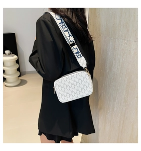 Detail of cream crossbody bag with M-letter embossing and wide decorative strap