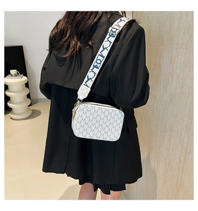 White mini crossbody bag with grey M pattern and wide woven shoulder strap shown on model