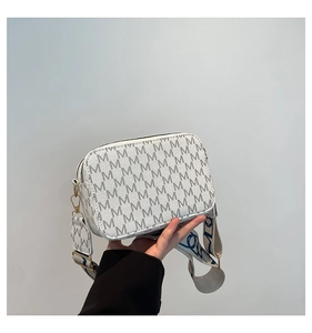 Detailed view of white crossbody bag with M-pattern and wide patterned shoulder strap