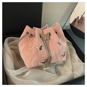 Detailed view of pink drawstring bucket bag with silver butterfly charms and pearl tassels