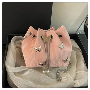 Detailed close-up of pink pleated bucket bag with silver butterfly charms and pearl tassels