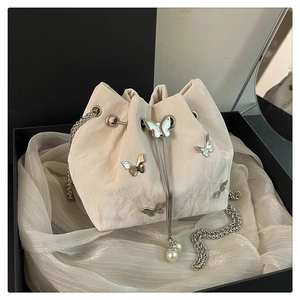 Detail of off-white bucket bag with silver butterfly ornaments and pearl drawstring accents