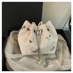 Detail of cream drawstring bucket bag with silver butterfly charms and pearl accents