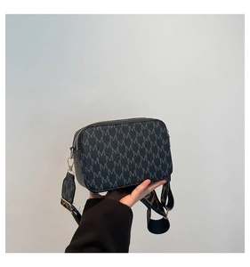 Detail of black crossbody bag with M-letter print and adjustable wide fabric strap
