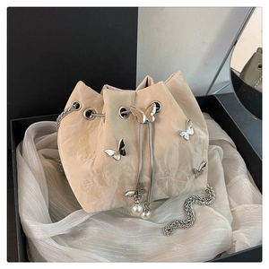 Detail of beige bucket bag featuring silver 3D metal butterflies and pearl drawstring