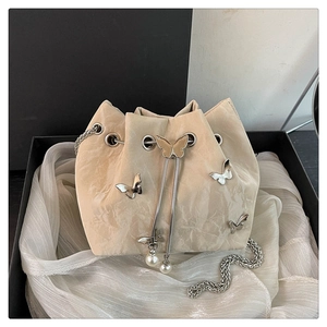 Detail of a beige drawstring bucket bag featuring silver butterflies and a pearl charm