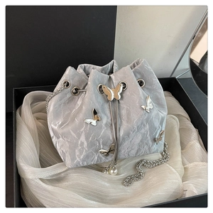 Detail of silver bucket bag with 3D metal butterflies and pearl drawstring accents