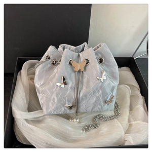 Detail of silver bucket bag with metallic butterfly accents and pearl drawstring charms