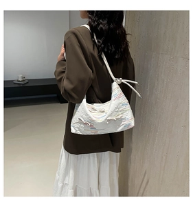 Detail of soft crescent shoulder bag featuring floral embroidery and white bows on textured fabric