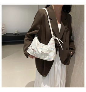 Detail view of white hobo bag featuring colorful embroidery and ribbon knot strap decoration