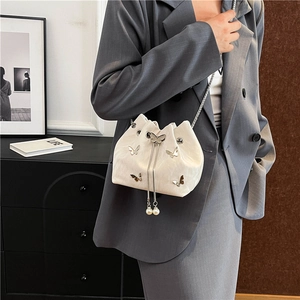 Elegant cream bucket bag with silver butterfly charms and pearl tassels on chain strap