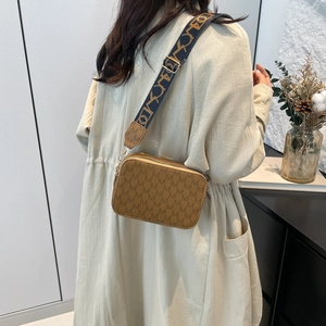 Brown monogram camera bag with wide jacquard strap shown in a modern lifestyle setting