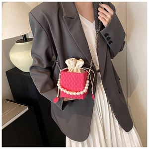 Dettaglio mini borsa intrecciata rosa con manico di perle e tracolla a catena d'oro