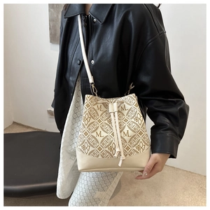 Detail of cream bucket bag with brown monogram pattern and drawstring closure