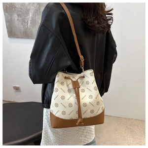 Detail of printed bucket bag with drawstring closure and leather patchwork strap