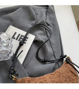Detail of leopard print crescent bag featuring sturdy knotted rope shoulder strap and suede texture