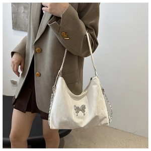 Détail du sac à bandoulière blanc avec papillon argenté et texture en cuir synthétique plissé