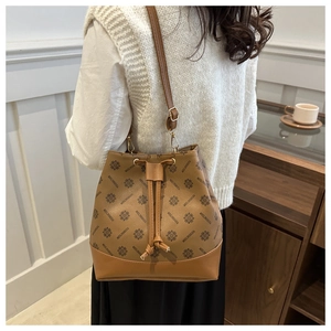 Detailed view of brown bucket bag with monogram pattern and leather drawstring closure