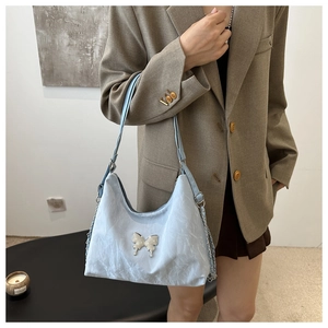 Détail du sac sous le bras plissé bleu clair avec un pendentif nœud en strass argenté
