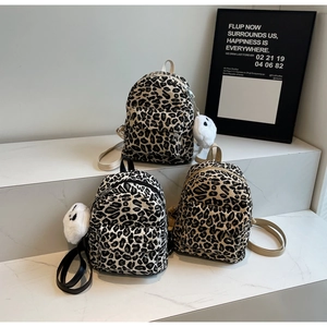 Dettaglio di mini zaini con stampa leopardata e ciondoli di peluche su marmo