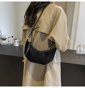 Schwarze Schultertasche in Halbmondform aus Wildleder-Optik am Model getragen