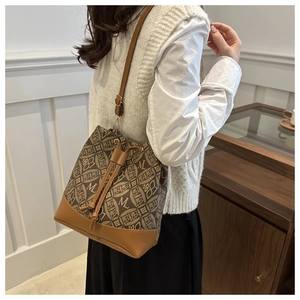 Detail of retro monogram bucket bag showing brown drawstring closure and shoulder strap