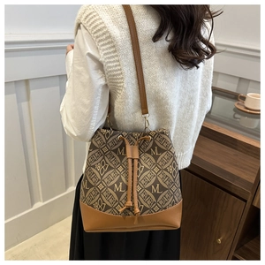Rear view of a model wearing the vintage monogram canvas drawstring bucket bag in brown