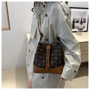 Detail of vintage bucket bag with monogram pattern and camel leather straps on a model