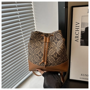 Detail of retro brown bucket bag featuring monogram print and drawstring closure