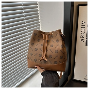 Detail view of the brown bucket bag showing geometric monogram pattern and drawstring closure