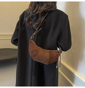 Nahaufnahme einer braunen Croissant-Tasche aus Wildleder mit dekorativem Knoten-Detail