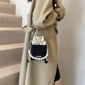 Elegante borsa a secchiello nera con manico di perle e tracolla dorata indossata