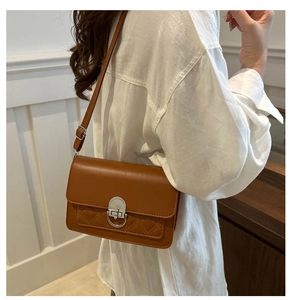 Detail van een bruine vintage crossbodytas met ruitstiksel en metalen draaisluiting
