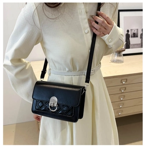 Detail van zwarte crossbody tas met zilveren draaisluiting en ruitvormig gewatteerd vak