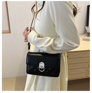 Detail van zwarte crossbodytas met gewatteerde textuur en zilveren gesp op model