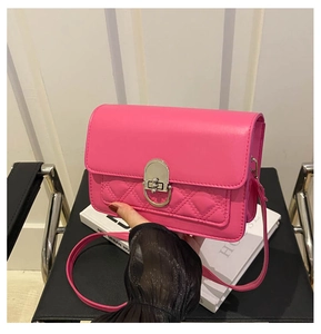 Detail van rozerode vierkante crossbodytas met gewatteerde stiksels en zilveren sluiting