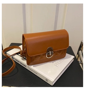 Detail van de karamelbruine crossbodytas met gewatteerde stiksels en zilveren draaisluiting