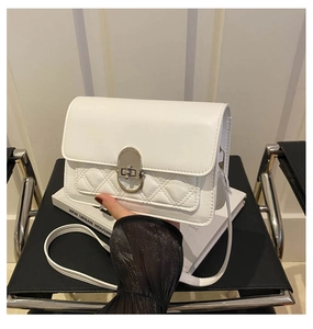 Detail van witte leren crossbody tas met ruitpatroon en zilverkleurige metalen sluiting