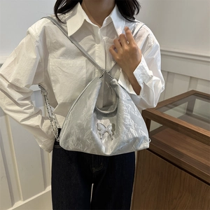 Sac fourre-tout plissé argenté avec détail de nœud porté par un mannequin en style