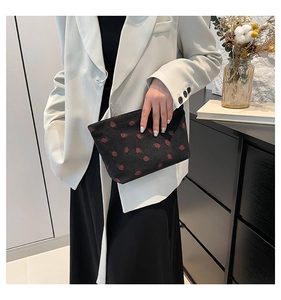Dettaglio di pochette in velluto a coste con motivo a fragole tenuta in mano in interni moderni