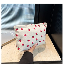 Dettaglio della borsa trucco in velluto a coste con ricami fragole rosse