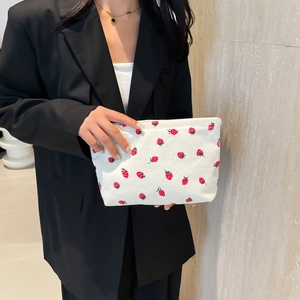 Sac cabas minimaliste en velours côtelé blanc à motif fraises porté par un mannequin en costume