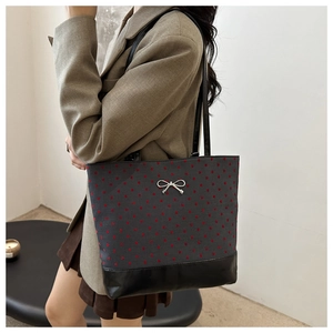 Dark grey canvas tote with red heart embroidery and silver bow charm shown on shoulder