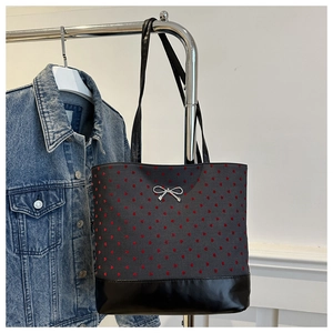 Close-up of gray canvas tote with red heart embroidery and black leather trim detail