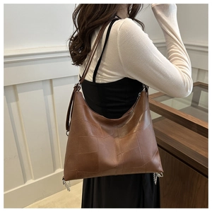 Détail du sac hobo vintage marron avec coutures géométriques et longues bandoulières